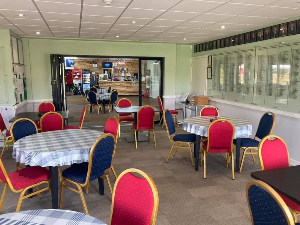 One of the clubhouse lounges, tables laid with red and blue chairs
